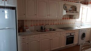Eine Küche mit weißen Schränken, einem Spülbecken, einer Waschmaschine und einem Kühlschrank.