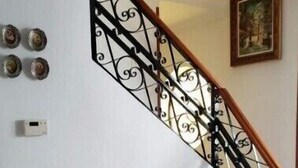 Eine Treppe mit aufwendiger schwarzer Geländer, einer Holztür und einem gefliesten Boden.