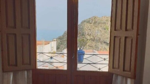 Ein Zimmer mit Holztür und Zugang zu einem Balkon mit Blick auf eine gebirgige Landschaft.