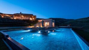 A modern pool area with a house in the background. - Dimora Montefiore 11, Emma Villas (Montefiore dell'Aso)
