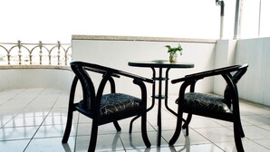 A balcony with two chairs and a small table, featuring a potted plant. - 19 wuo wuo hotel (Hualien City)