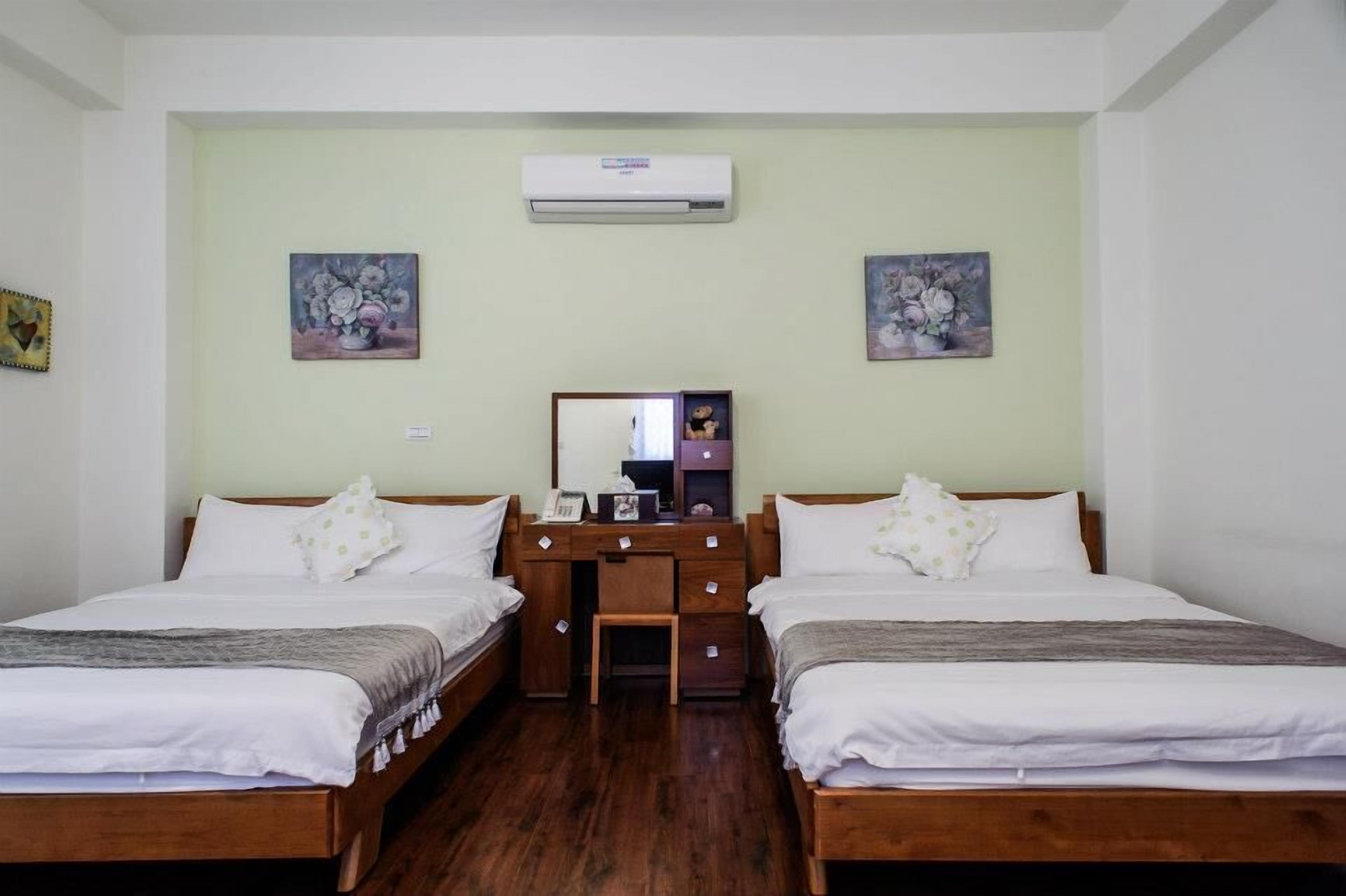 A room with two wooden beds, a desk with a mirror, and two wall-mounted air conditioners.