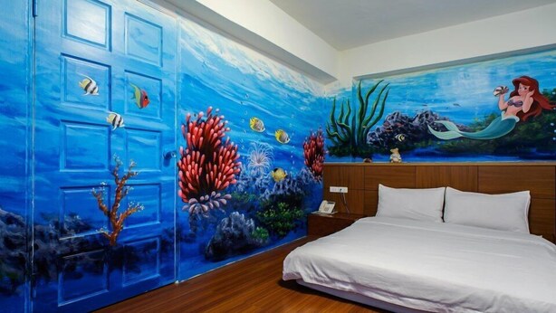 A bedroom with a mural of an underwater scene on the wall, a bed with white linens, and a wooden headboard. - 19 wuo wuo hotel (Hualien City)