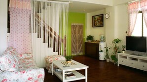 A living room with a sofa, coffee table, TV, and plants. - 19 wuo wuo hotel (Hualien City)