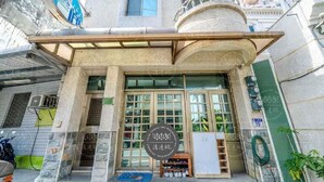 A building with a stone facade, large windows, and a sign with Chinese characters. - 19 wuo wuo hotel (Hualien City)