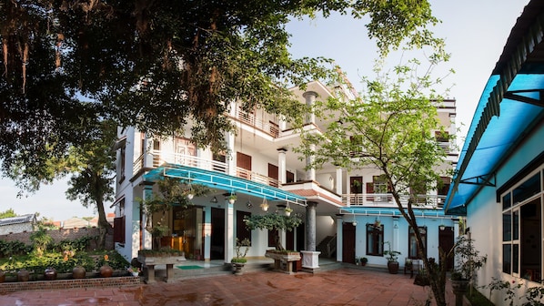 A multi-story building with a covered courtyard, columns, and potted plants.