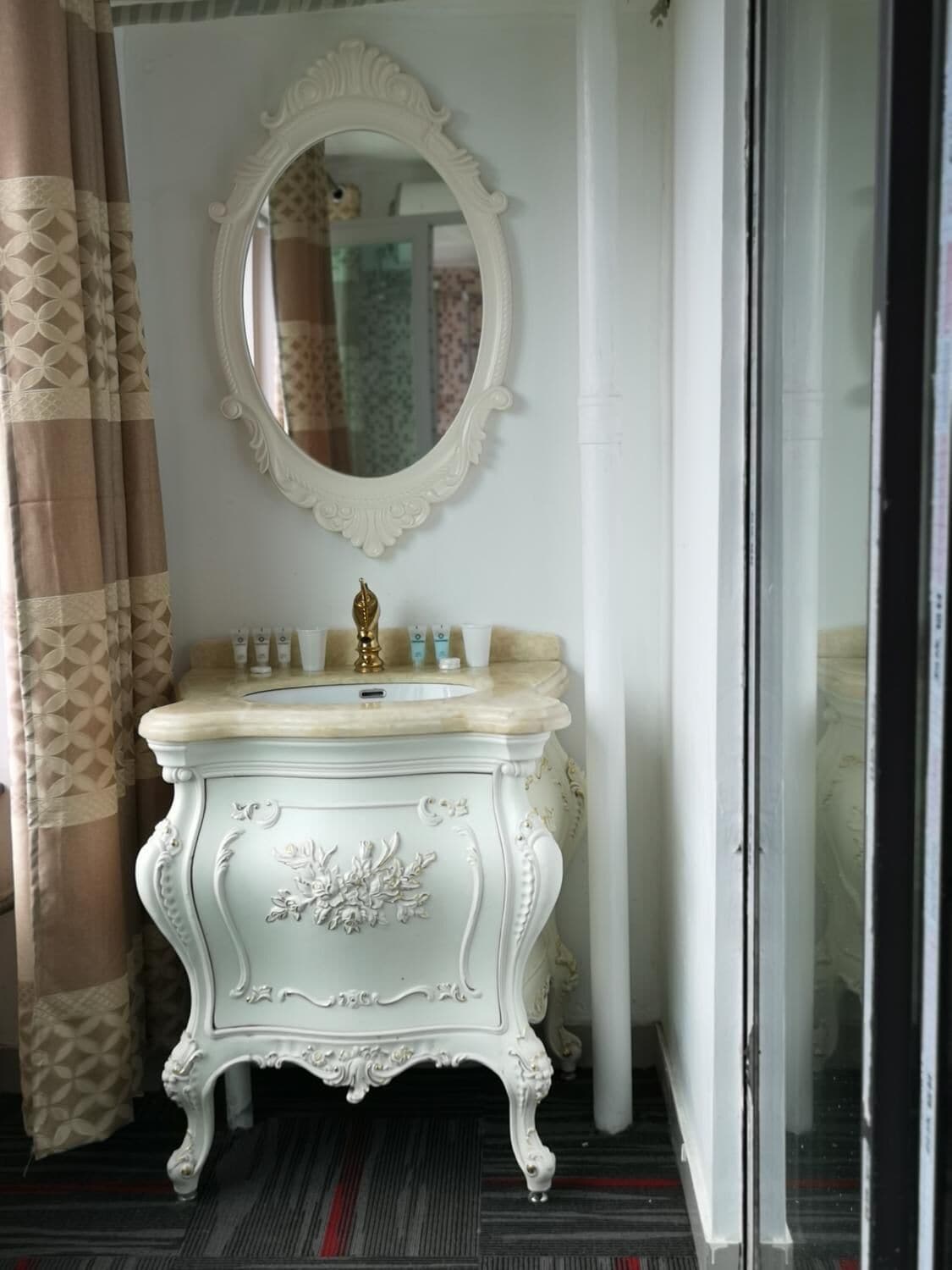 A white vanity with a mirror, a gold faucet, and toiletries.