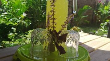 A clear glass pitcher with a blue lid and a green base, placed on a wooden table outdoors.