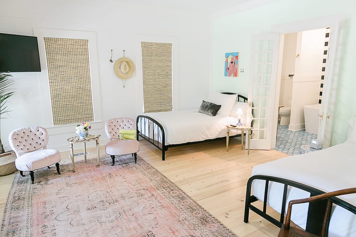 A bedroom with a bed, two chairs, a small table, and a rug.
