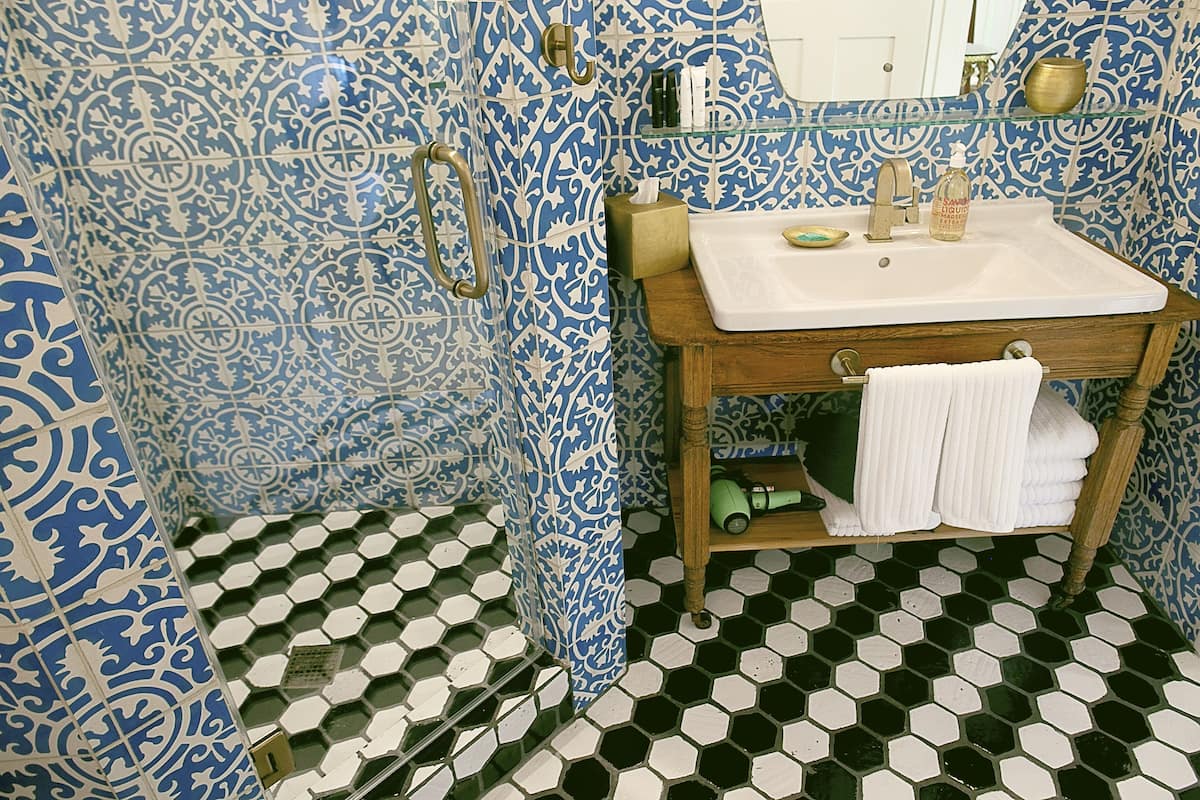 A bathroom with a sink, mirror, and patterned tiles.