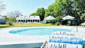 Ein Swimmingpool mit einem Schild, auf dem 'Delight, Champ a go go, Petilland' steht, und einer Liege im Vordergrund.