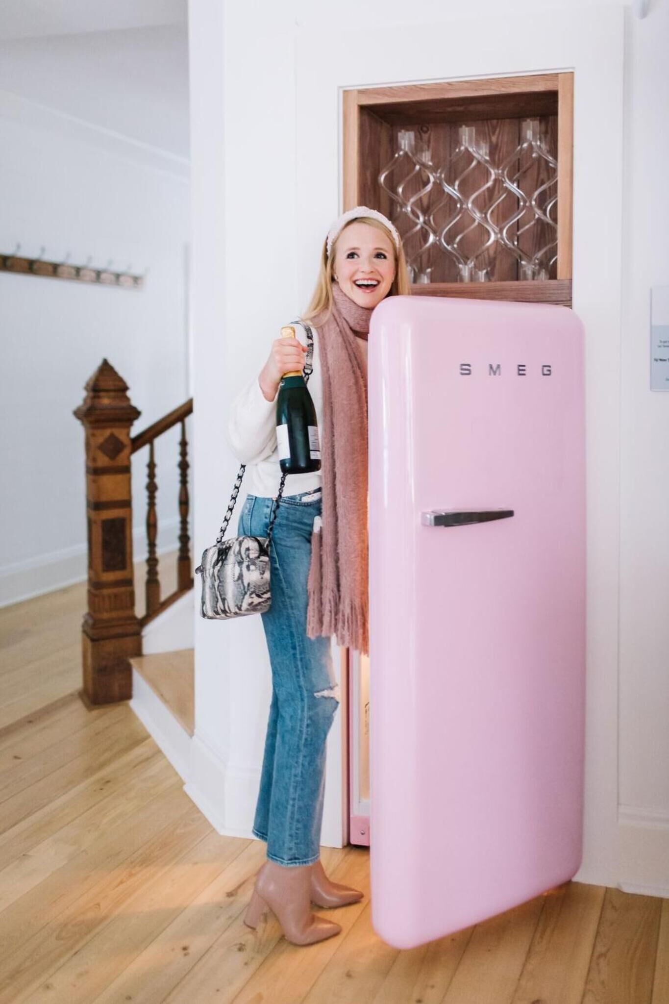 En person som står bredvid ett rosa kylskåp av märket ”SMEG”.