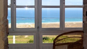 A room with a large window overlooking a beach. - Unique oceanfront retreat with fantastic views of the wild natural space (Carballo)