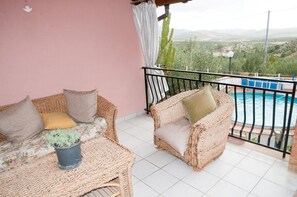 Ein Balkon mit Korbmöbeln, einem Pool und Blick auf die Landschaft.
