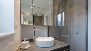 A modern bathroom with a round sink, a large mirror, and a glass-enclosed shower. - Suite Sant 'Agostino behind the cathedral (Palermo)