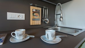 A modern kitchen with two white cups on saucers, a knife, a cutting board, a faucet, and a power outlet. - Suite Sant 'Agostino behind the cathedral (Palermo)