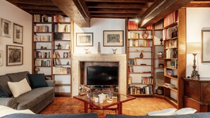 Ein gemütliches Wohnzimmer mit Kamin, Fernseher und einer Bücherwand voller Bücher.