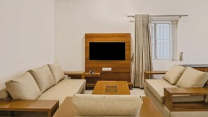 Un salon moderne avec un téléviseur à écran plat, deux canapés, une table basse et une fenêtre avec des rideaux.