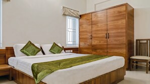 Une chambre à coucher avec un lit en bois, des oreillers verts, une armoire en bois et une fenêtre avec des barreaux.