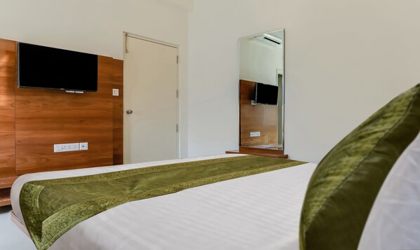 A hotel room with a bed, a TV mounted on the wall, and a mirror.