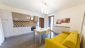 Eine moderne Küche mit Esstisch und Stühlen, einem gelben Sofa und einer karierten Spritzschutzleiste.