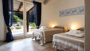 A room with two beds, a sliding glass door leading to an outdoor area, and a decorative wall piece. - Charming villa with magnificent sea view (Santa Teresa di Gallura)