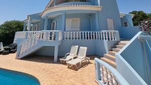 A large blue house with a swimming pool, a covered patio, and a staircase leading to a balcony. - Villa with a privileged panoramic view (Loule)