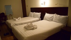 Two single beds with white linens and pillows, a bedside table, a nightstand, a whiteboard, and a chair. - Flamingo Guest House (Bahir Dar)