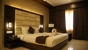 A spacious hotel room with a large bed, a nightstand with a phone, and a lamp. - West Fort Hotel (Bengaluru)