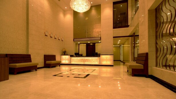 A lobby with a reception desk, benches, and a chandelier. - West Fort Hotel (Bengaluru)