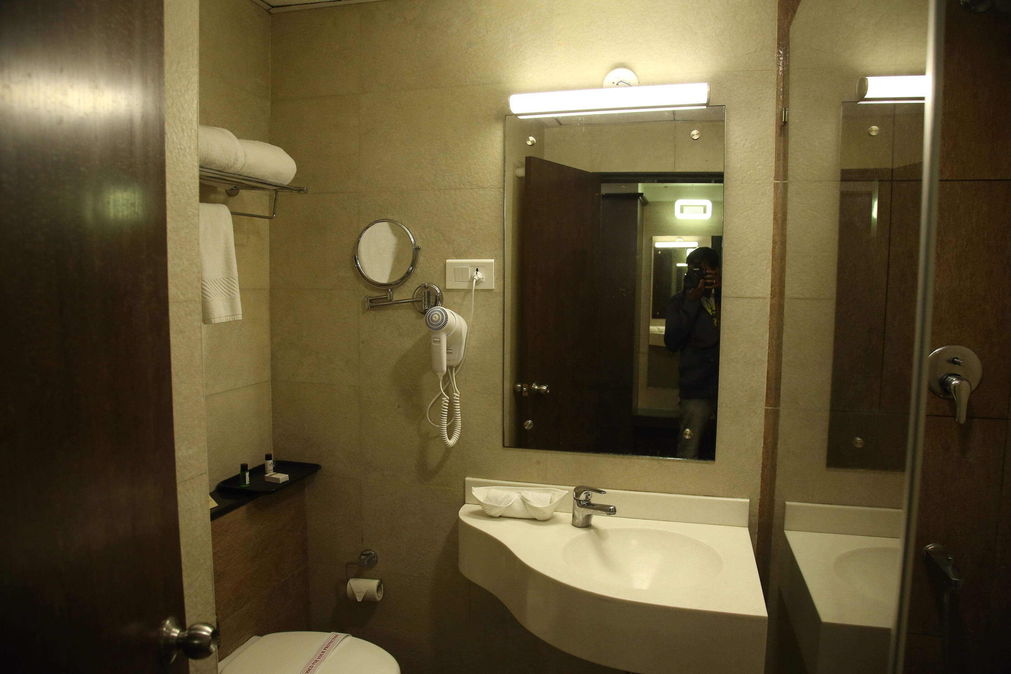 A bathroom with a toilet, two sinks, a mirror, a towel rack, and a hairdryer.