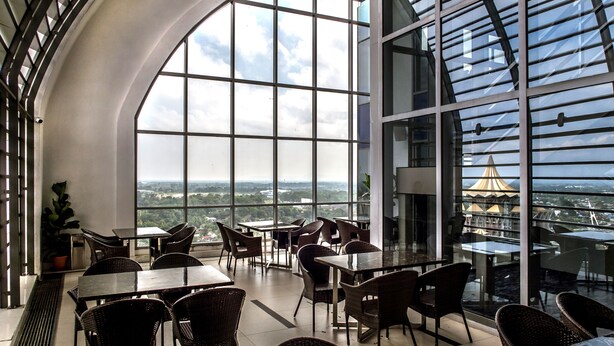 A modern indoor dining area with large windows offering a city view. - Astana Wing - Riverside Majestic Hotel (Kuching)