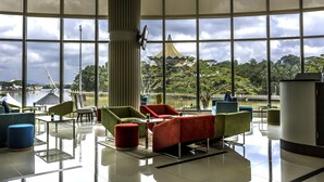 A spacious lobby with modern furniture, large windows offering views of a bridge and greenery. - Astana Wing - Riverside Majestic Hotel (Kuching)