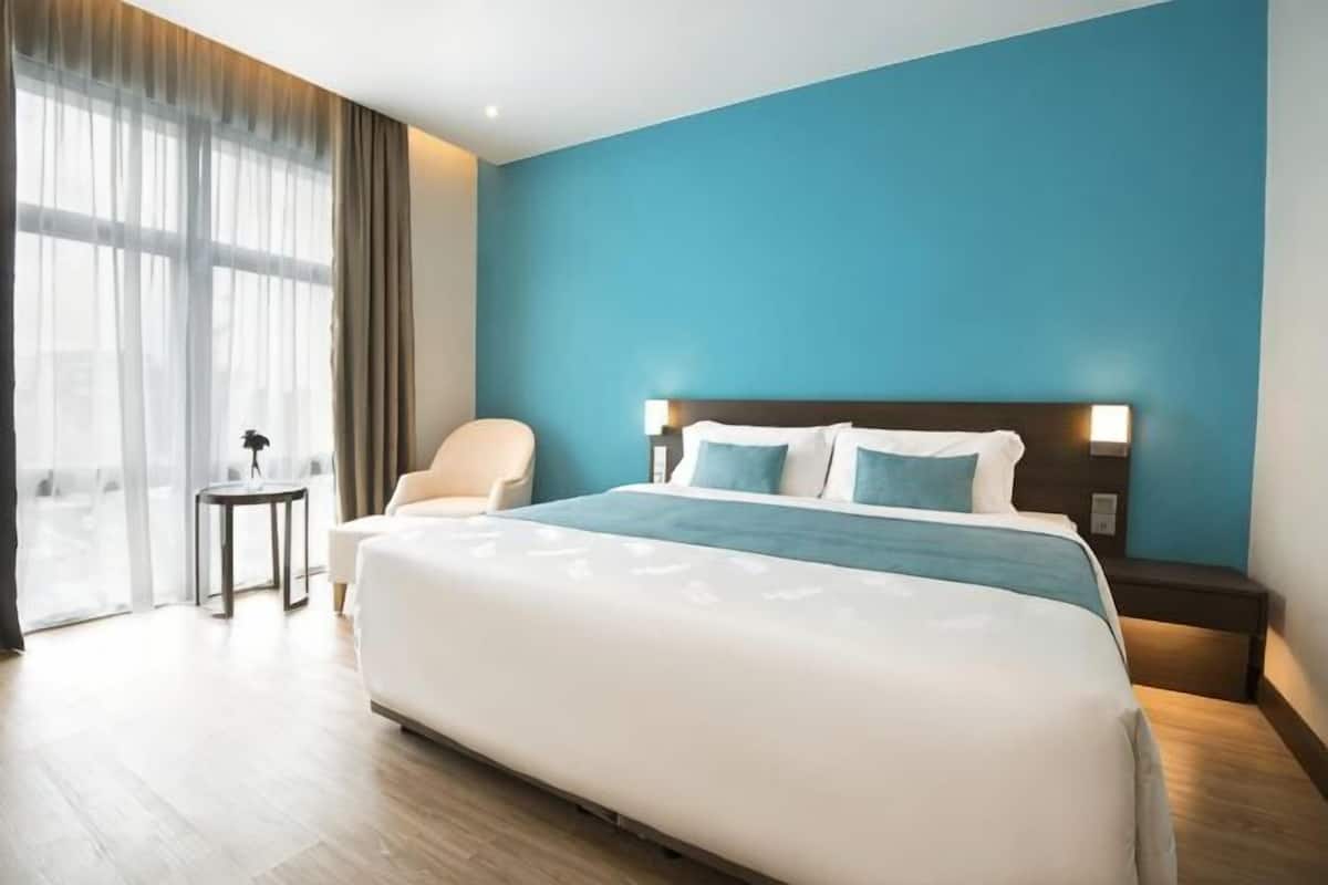 Una habitación de hotel con una cama grande, una mesita de noche, una silla y una pequeña mesa.