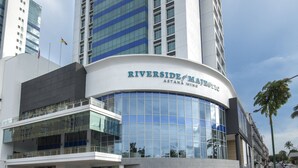 A tall, modern building with a curved facade and large windows. The name "Riverside" is visible on the lower part of the building. - Astana Wing - Riverside Majestic Hotel (Kuching)