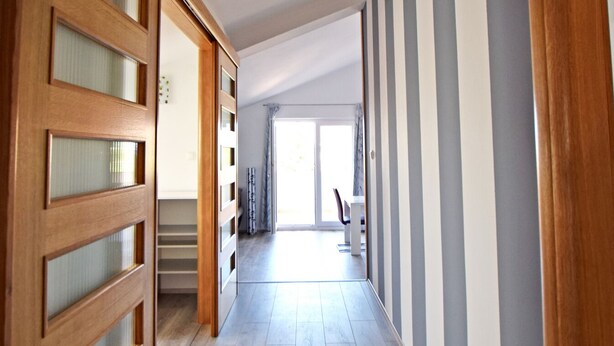 A hallway with wooden doors, a staircase, and a view into a room with a large window. - Apartment for up to 7 people with views to the mountains and the sea (Starigrad)