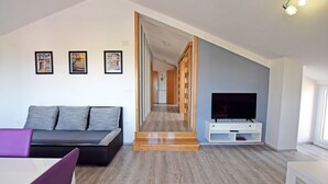 A modern living room with a sofa, a TV, and framed pictures on the wall. - Apartment for up to 7 people with views to the mountains and the sea (Starigrad)