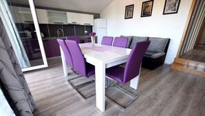 A modern kitchen with white cabinets and a dining area with a white table and purple chairs. - Apartment for up to 7 people with views to the mountains and the sea (Starigrad)