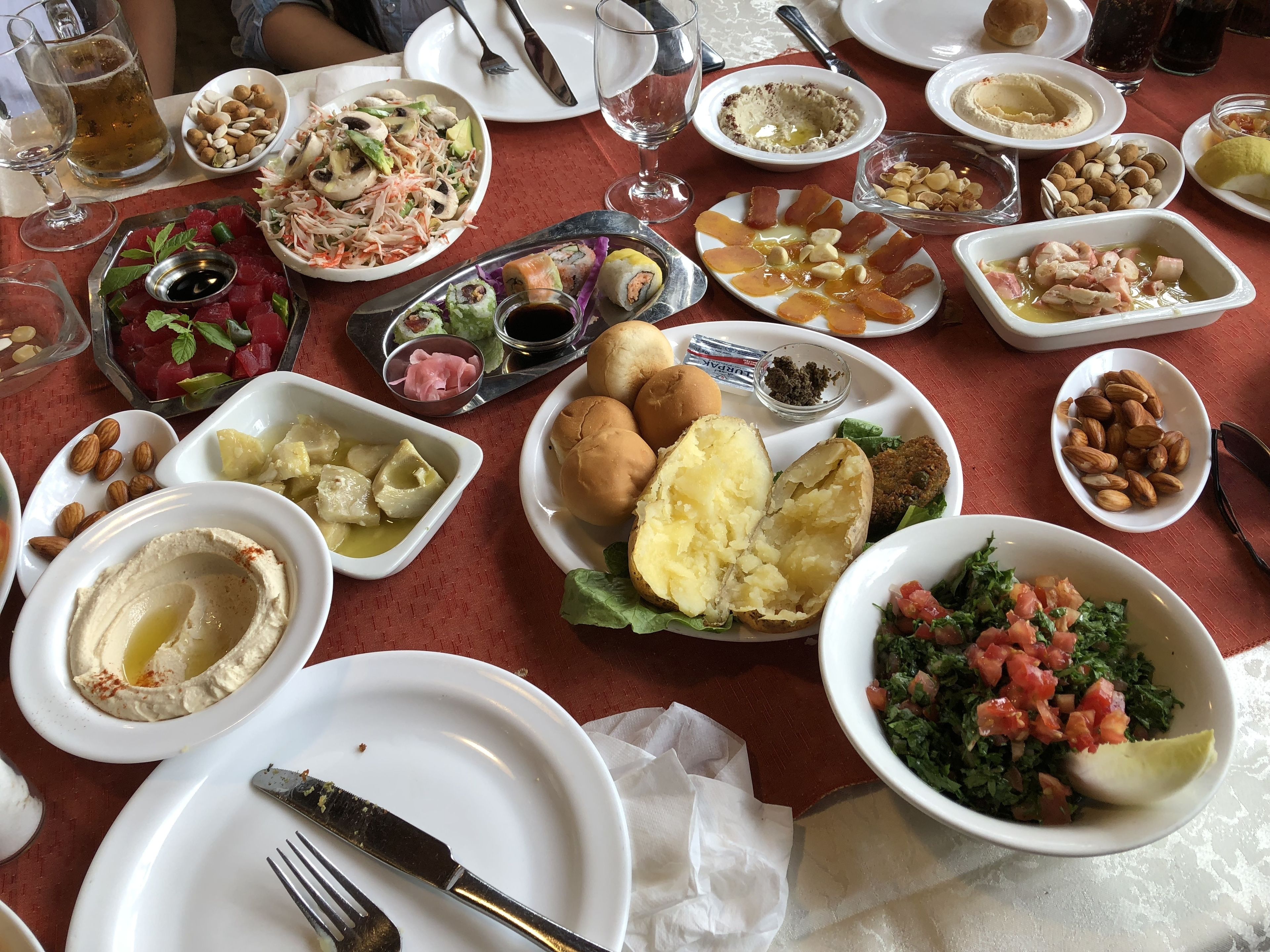 Een gedekte tafel met diverse gerechten, zoals hummus, salades en brood, wat duidt op een maaltijd.