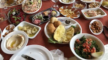 Een gedekte tafel met diverse gerechten, zoals hummus, salades en brood, wat duidt op een maaltijd.
