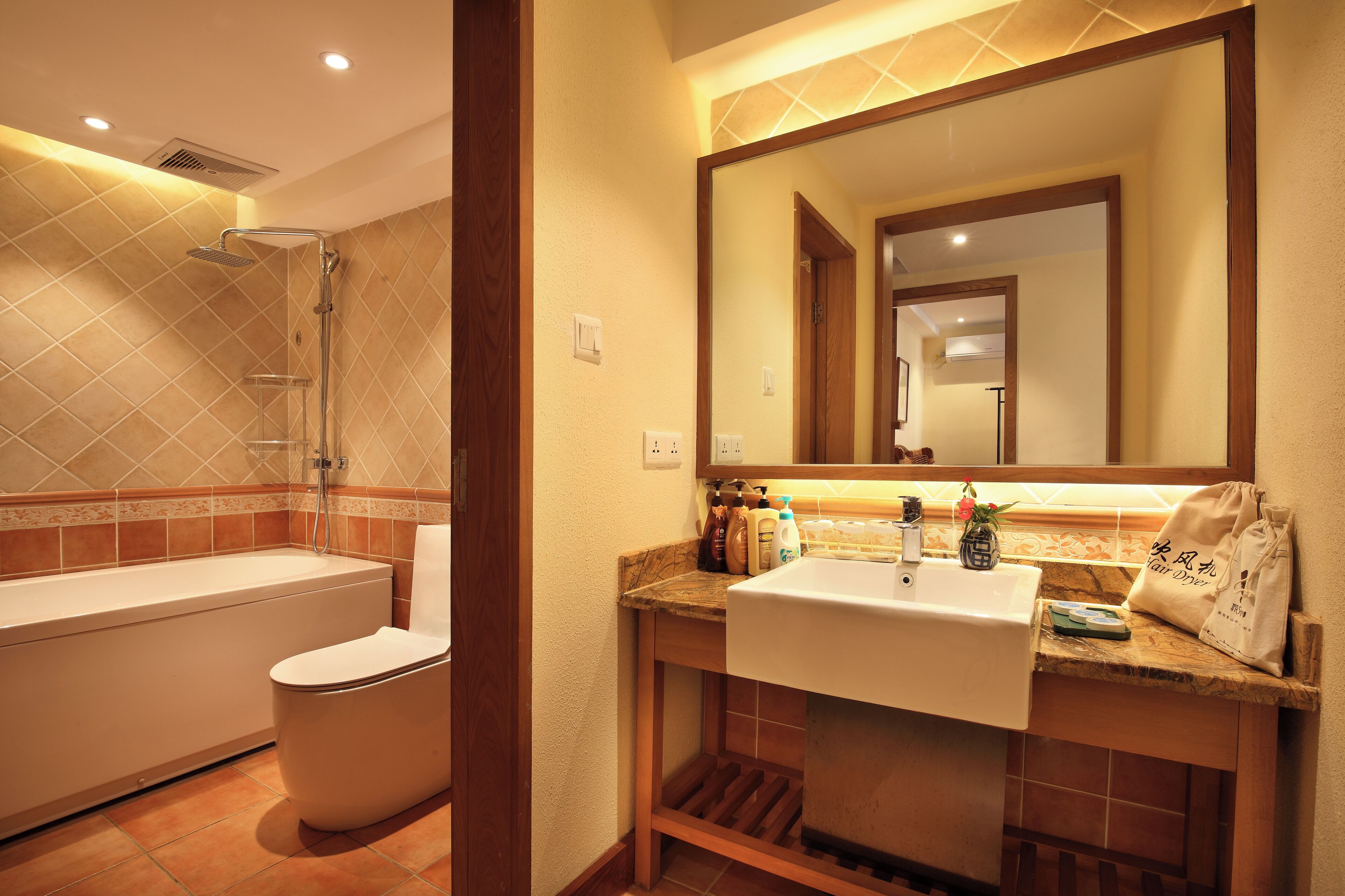 A bathroom with a bathtub, toilet, sink, and a large mirror.