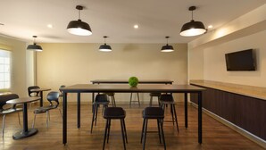 A conference room with a long table, six chairs, and three pendant lights.