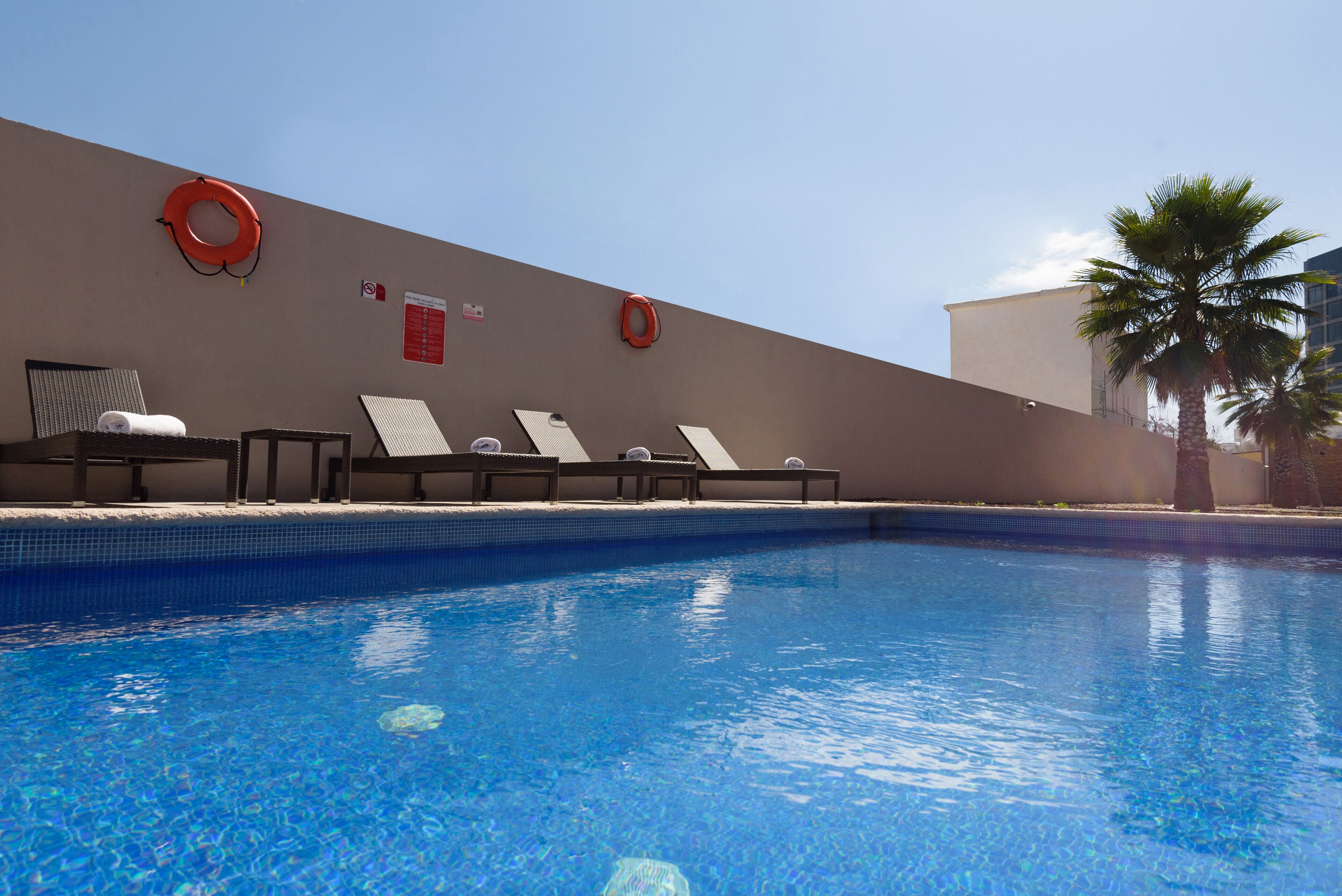 Une piscine équipée de chaises longues et de bouées de sauvetage fixées au mur.