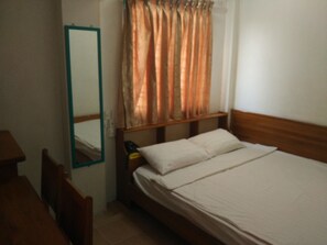 A bedroom with a wooden bed, a nightstand, a mirror, and a window with curtains. - Jade Hotel (Yangon)