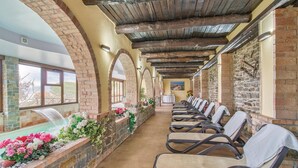 A covered outdoor seating area with brick walls, a stone bench, and a view of a waterfall. - Beautiful home in Stella Cilento with sauna (Stella Cilento)