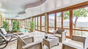 A spacious indoor area with large windows, wicker furniture, and a small pool. - Beautiful home in Stella Cilento with sauna (Stella Cilento)