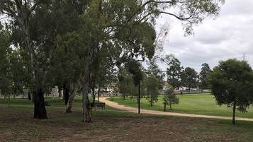 Un parque con árboles, un sendero de tierra y una zona cubierta de césped.