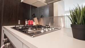 Ett modernt kök med en vit bänkskiva, en spis i rostfritt stål och en krukväxt.