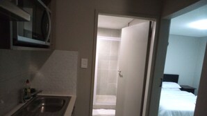 A narrow hallway leading to a bathroom with a shower and a bed in the adjacent room. - Apartment In Rosebank Johannesburg (Johannesburg)