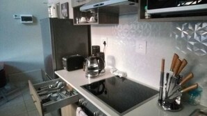A kitchen with a stove, microwave, and various utensils. - Apartment In Rosebank Johannesburg (Johannesburg)
